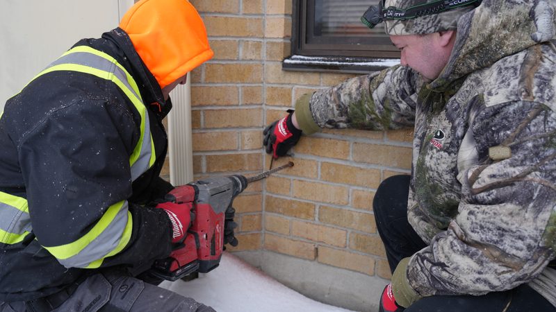 Technician drilling for cable runs