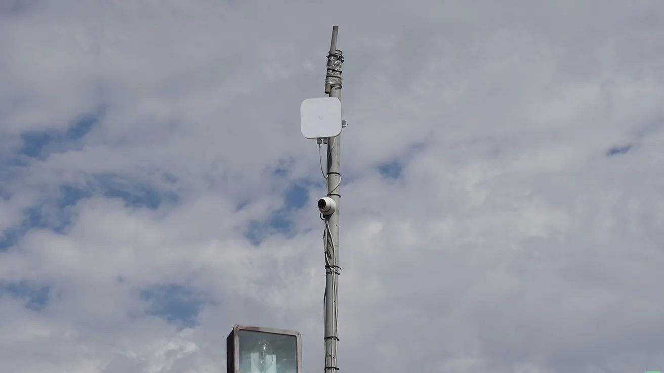Mast installation featuring a UniFi security camera and wireless access point for broad perimeter coverage
