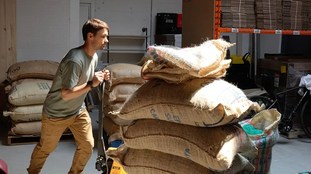 Production line worker moving specialty coffee bean bags in roasting facility