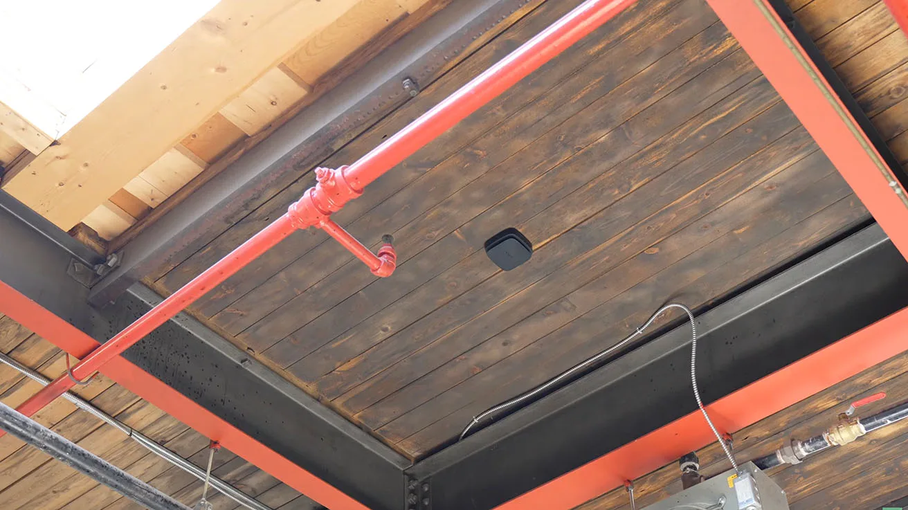 Ceiling-mounted Ajax FireProtect detector capturing smoke, heat, and carbon monoxide
