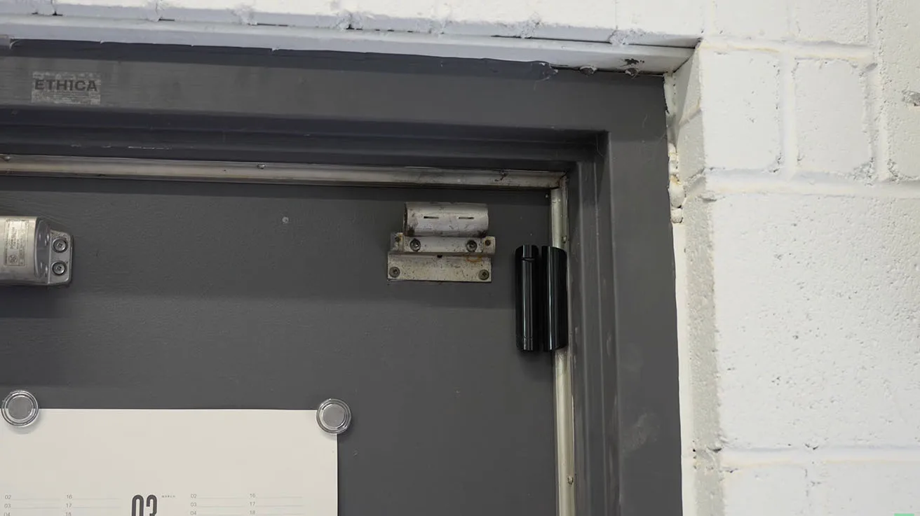 Ajax DoorProtect Plus with tilt and shock sensors mounted on heavy commercial overhead door