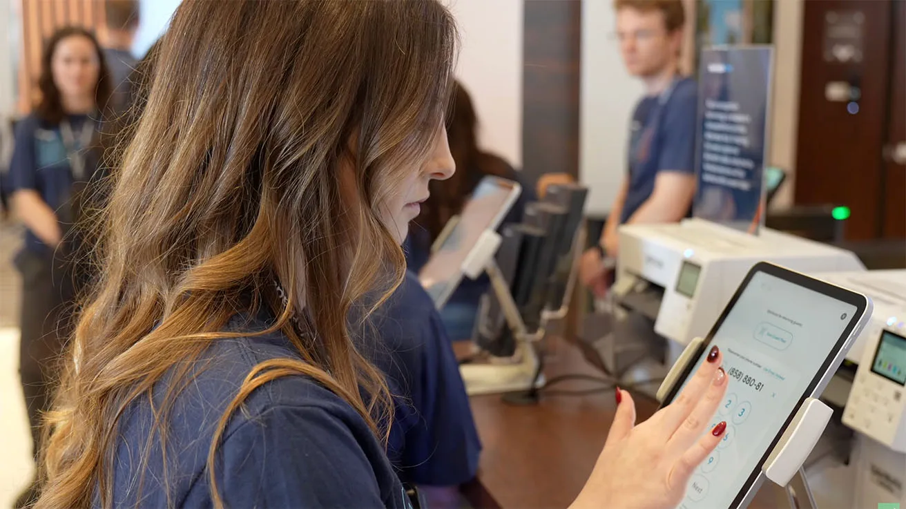 Visitor entering their phone number on a tablet to receive digital access credentials via SMS.