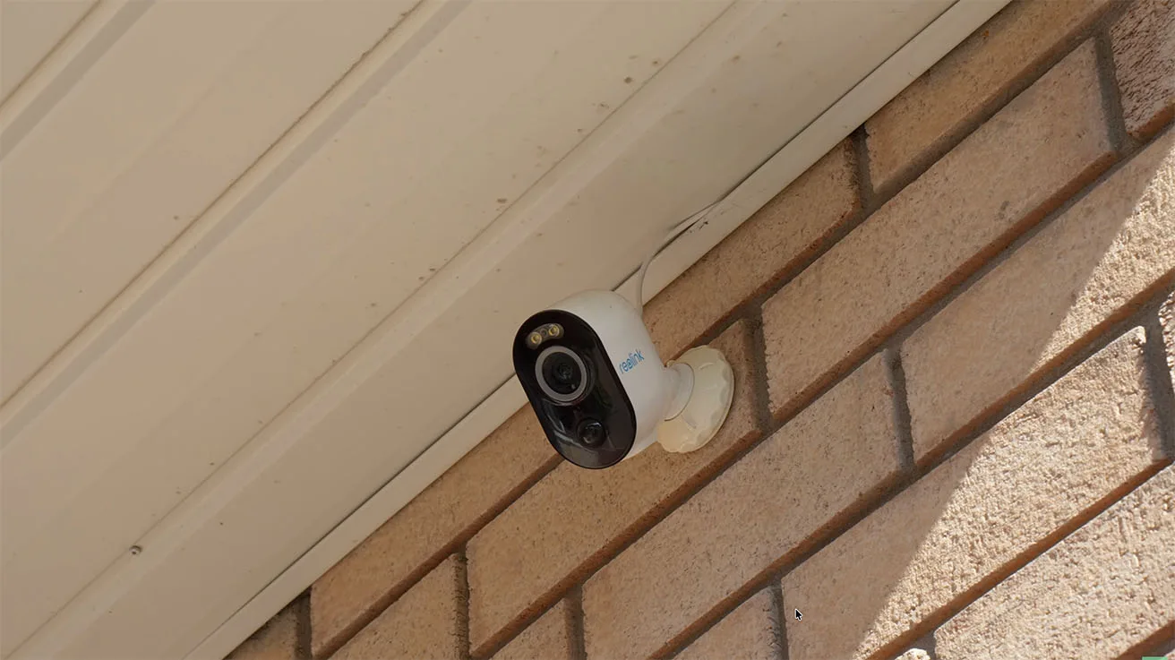 Reolink Argus 3 Pro mounted on a brick wall beneath the roof eaves near the front entrance