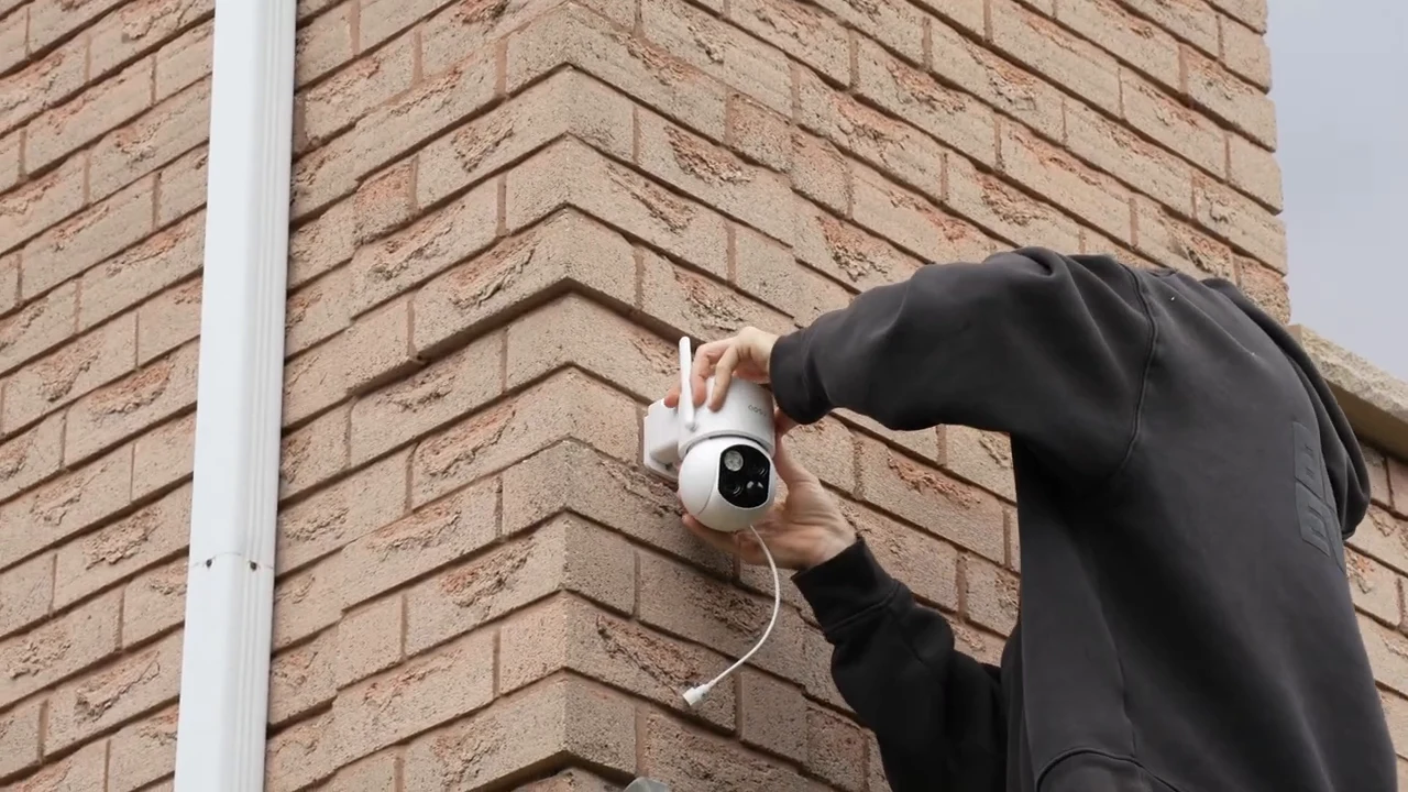 Homeowner attaching the SolarCam T2 to its exterior wall mount