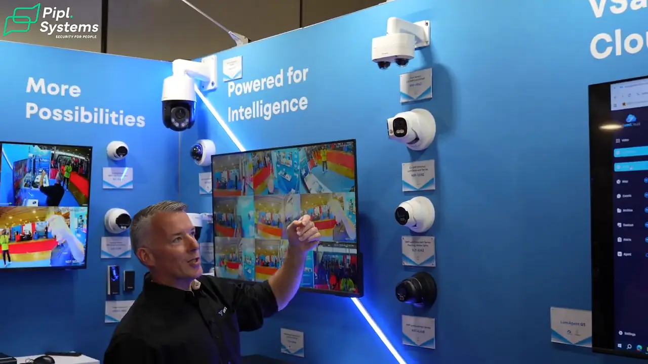 Chris Robertson points to cameras beside a monitor showing several surveillance views.