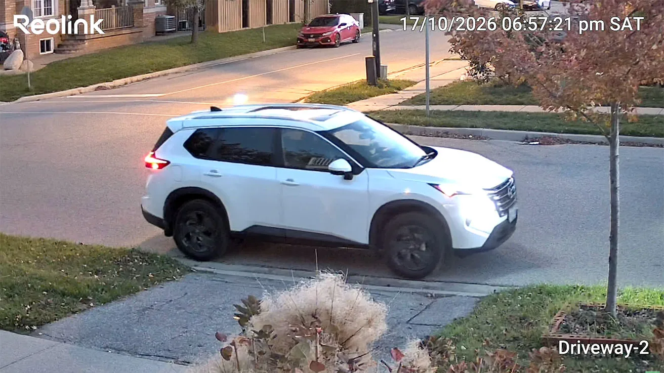 Tracking view of a white SUV entering the driveway