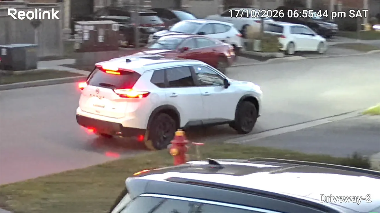 Tracking view of a white SUV leaving the driveway