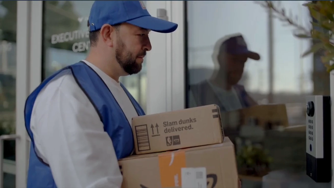 Delivery courier using an intercom at a glass building entrance.