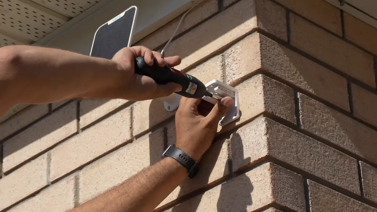 Installer securing the solar-panel mount beside the camera